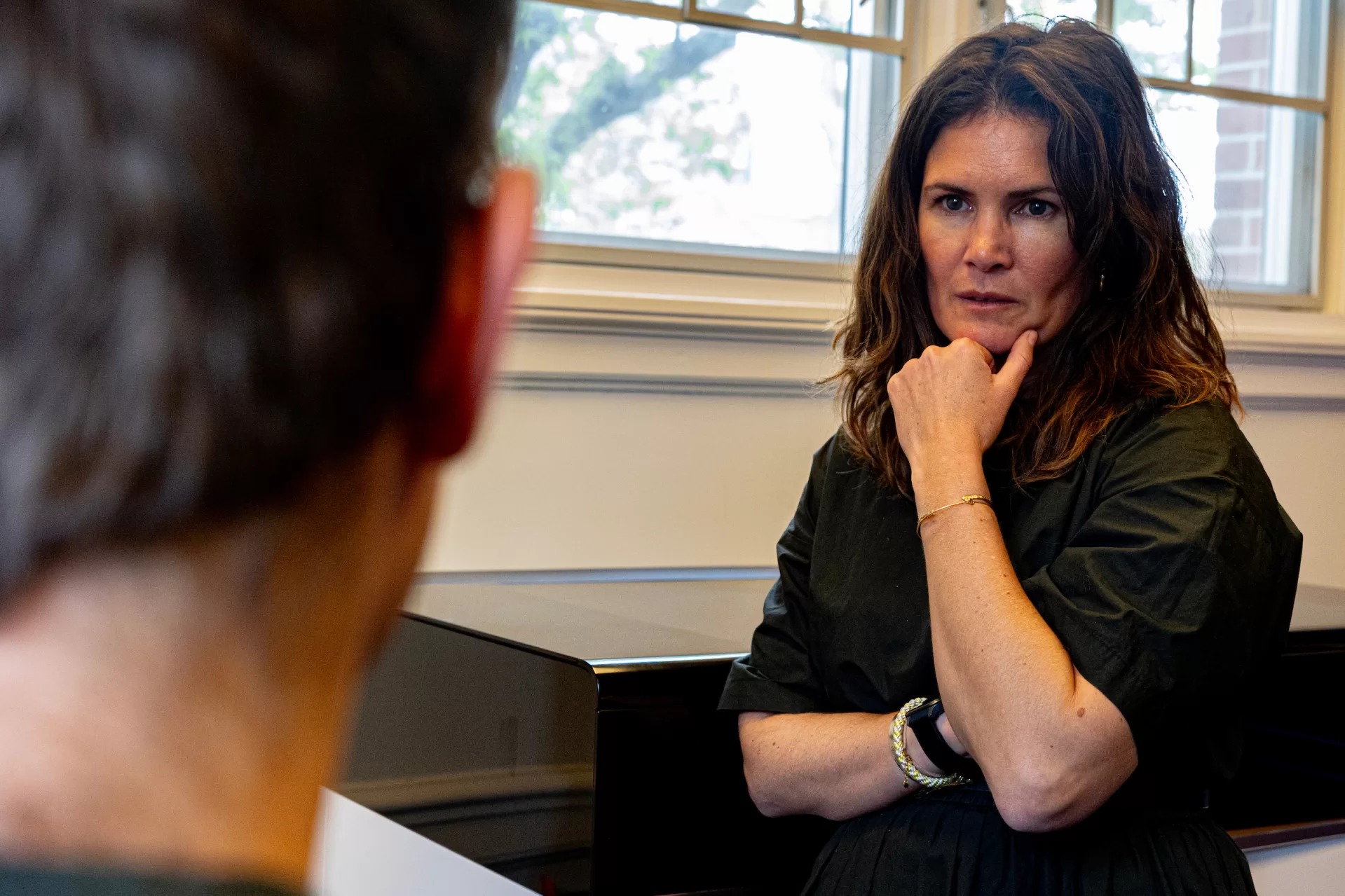 A woman talks to someone with her fist below her head, concentrating