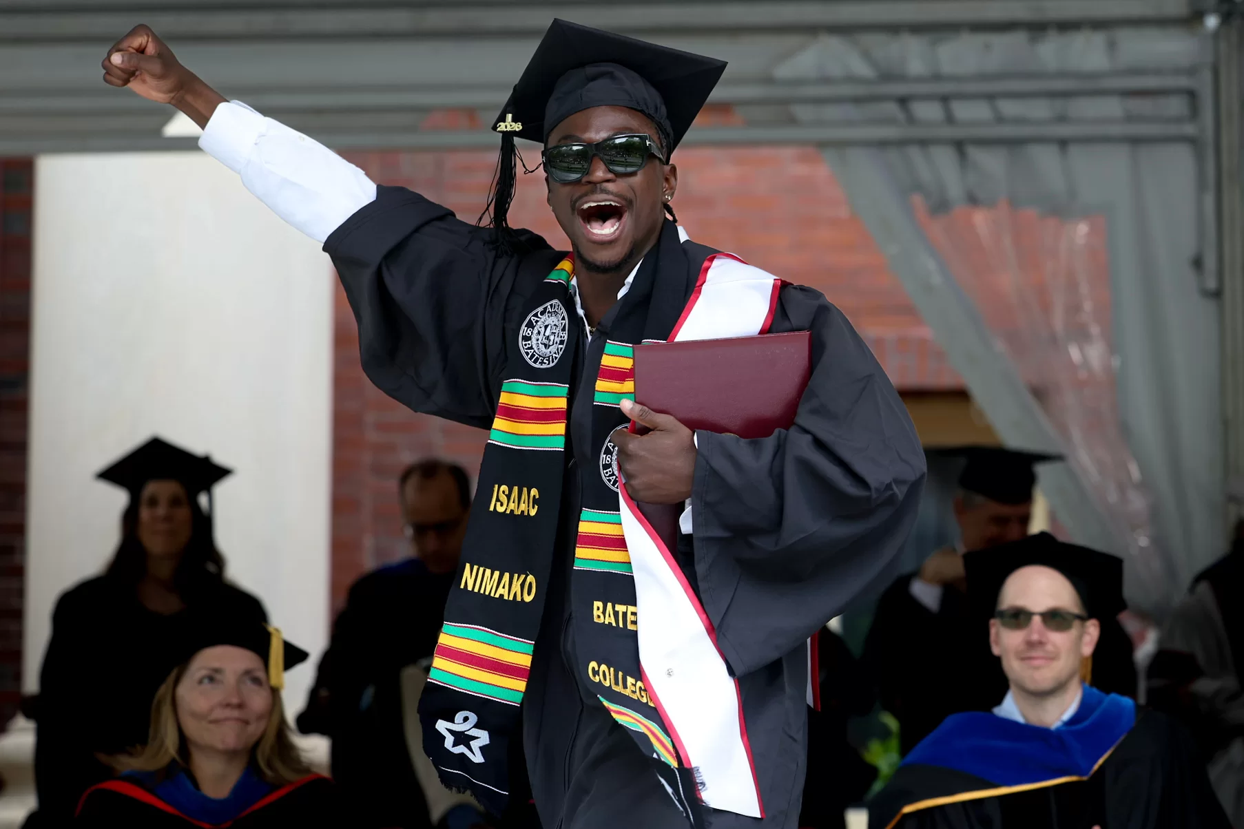 A graduate cheers while he walks across the stage