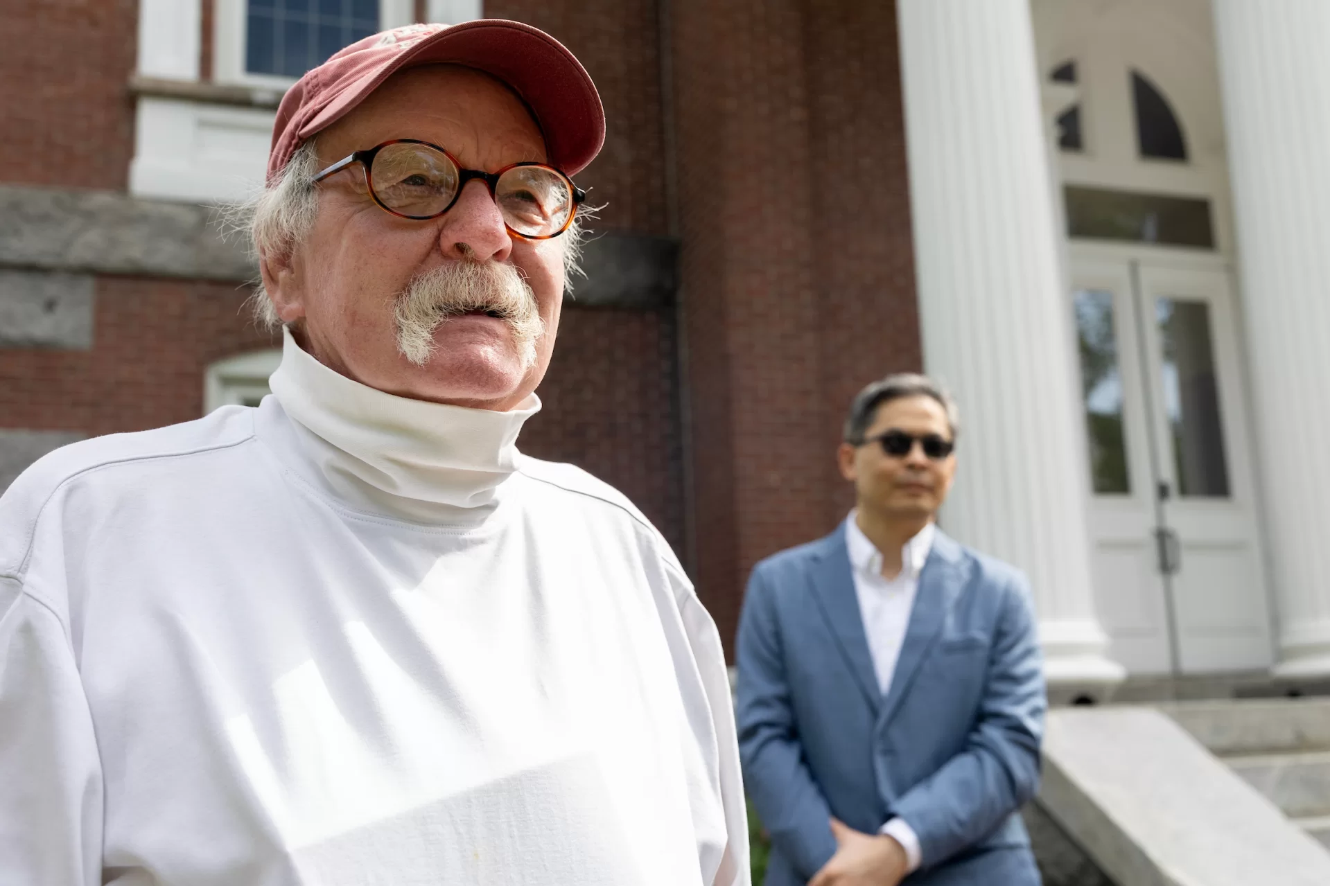 Ernie Ashton, retired school teacher who drives the Bobcat Express student shuttle, stands near Hathorn Hall at Commencement, May 31, 2026. “It's a pleasure to be here year after year,” he says. (Jay Burns/Bates College)
