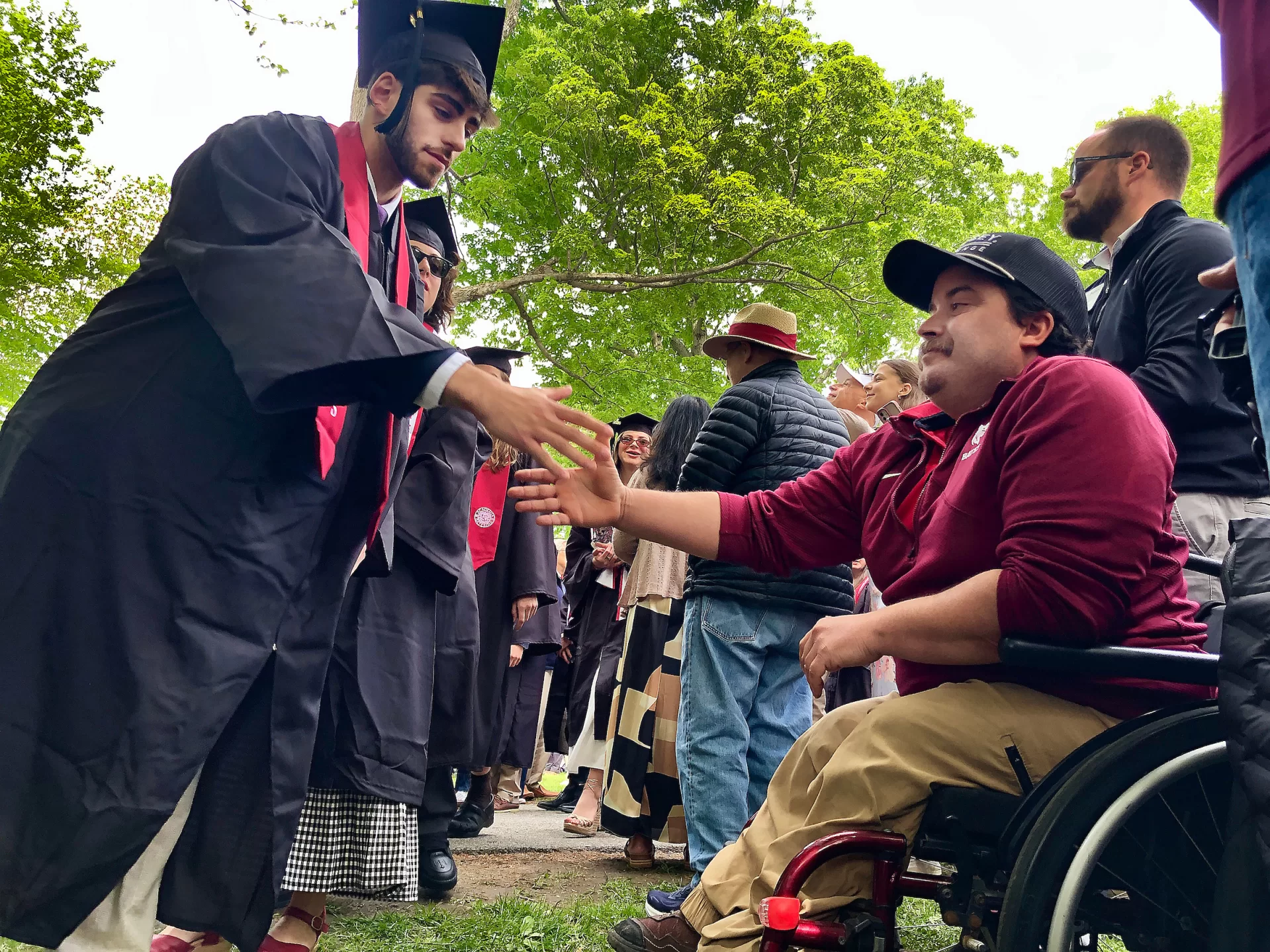 Zach Rosenthal ‘26 of Chicago reaches out to greet and thank avid Bates Athletics fan Jeremy Caron of Lewiston during the Commencement procession on May 31, 2026. (Jay Burns/Bates College)
