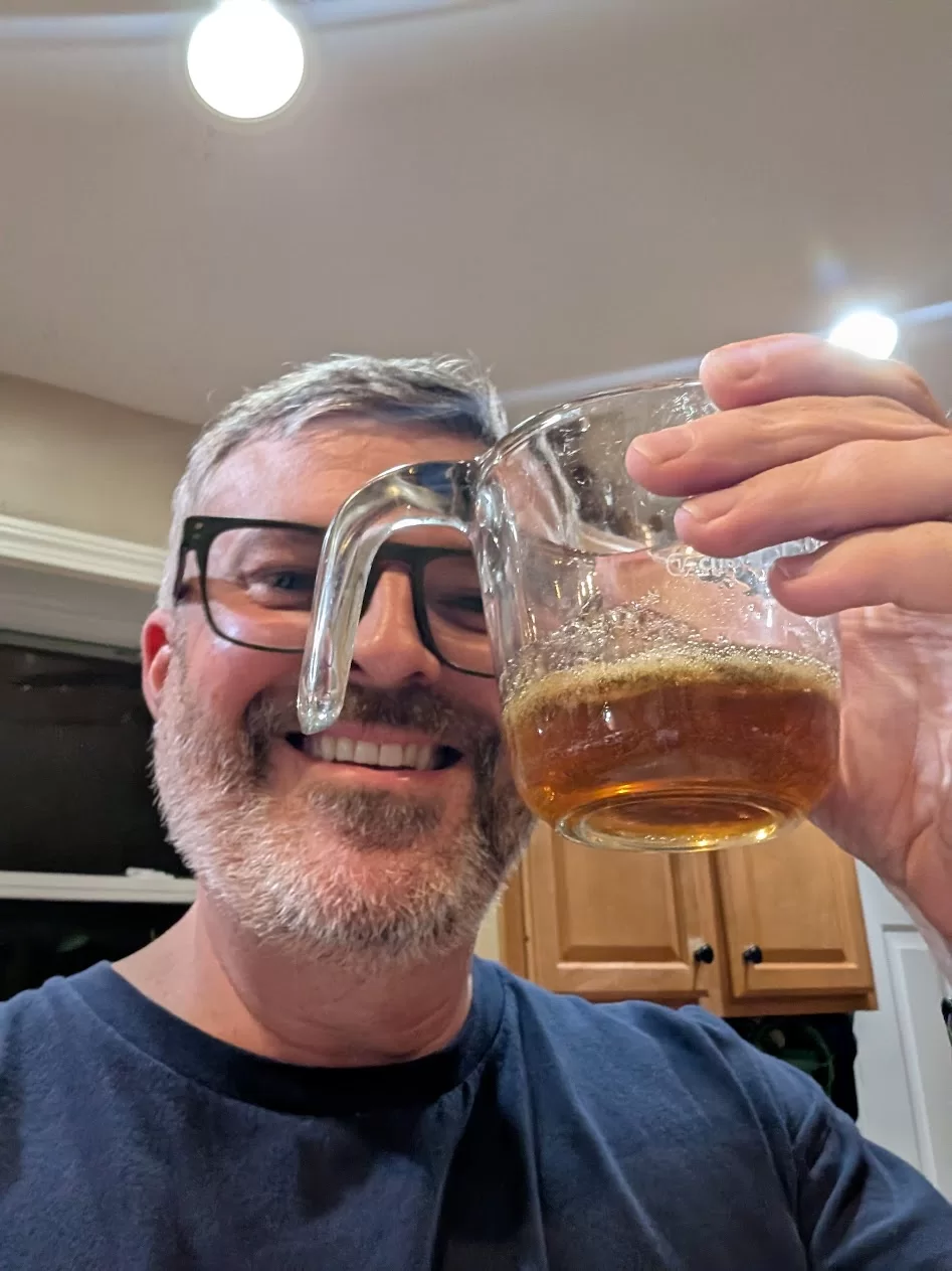 A man holding up a cup of maple syrup