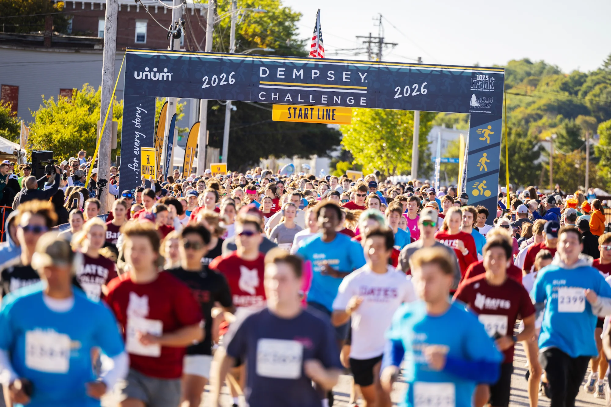 A group of runners run through the start line at a race
