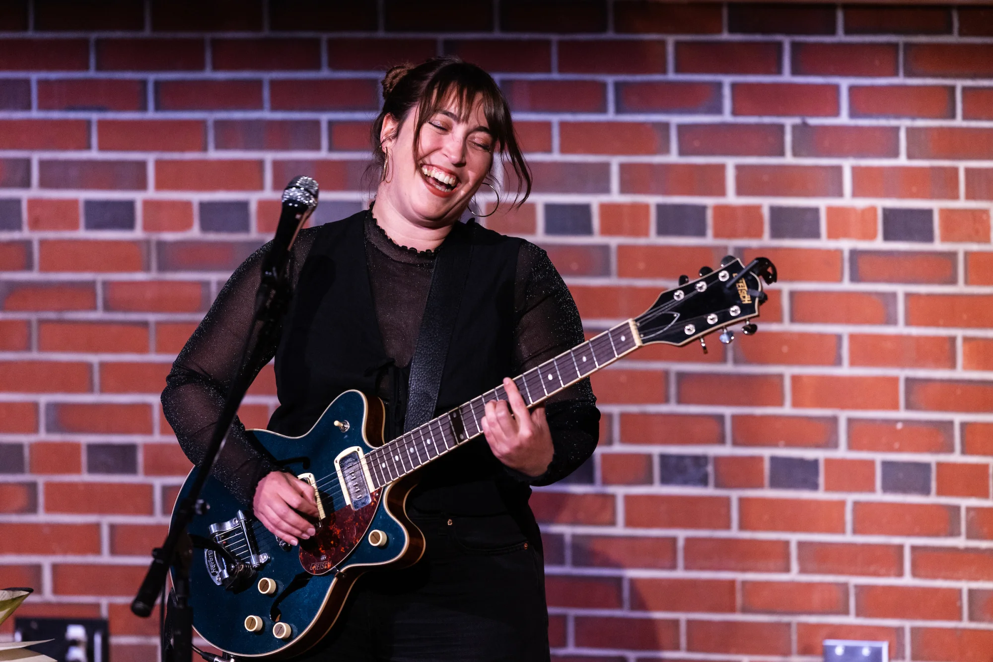  A woman smiles while playing an electric guitar onstage