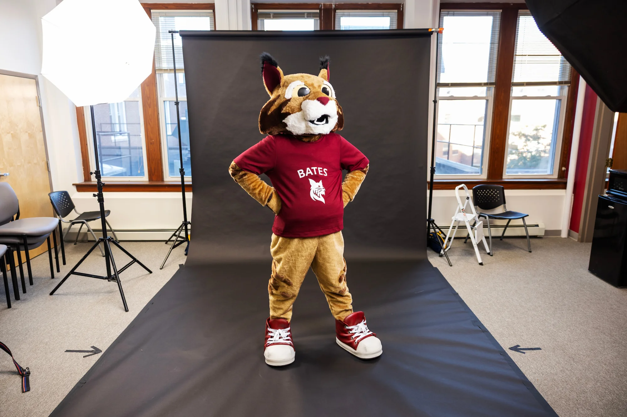 A mascot of a Bobcat standing in front of a black background set up in a room