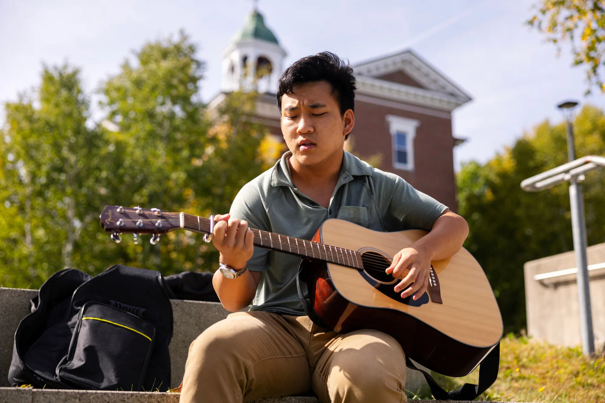 A man plays guitar while sitting outside