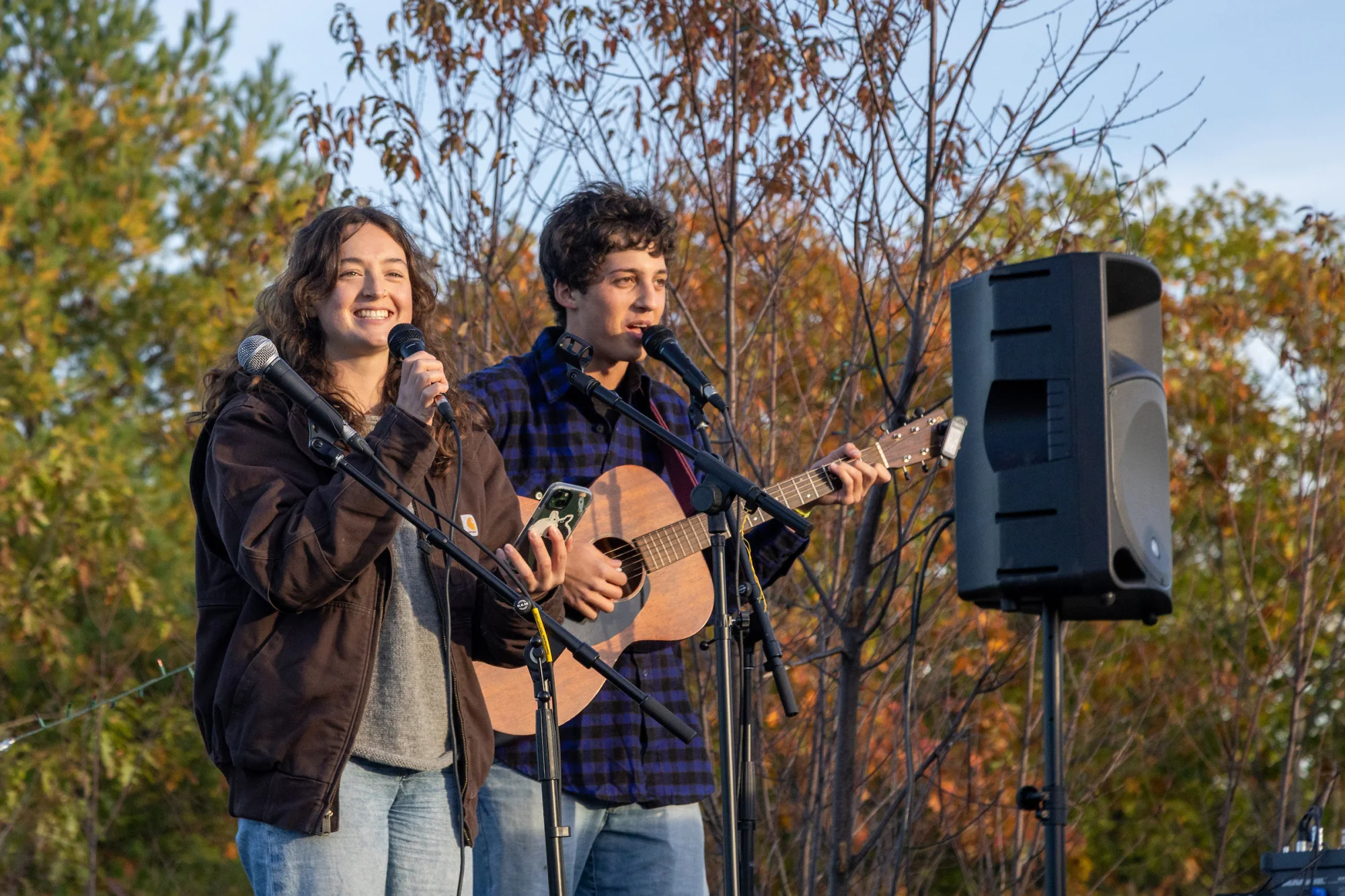 Two people smile while performing outside