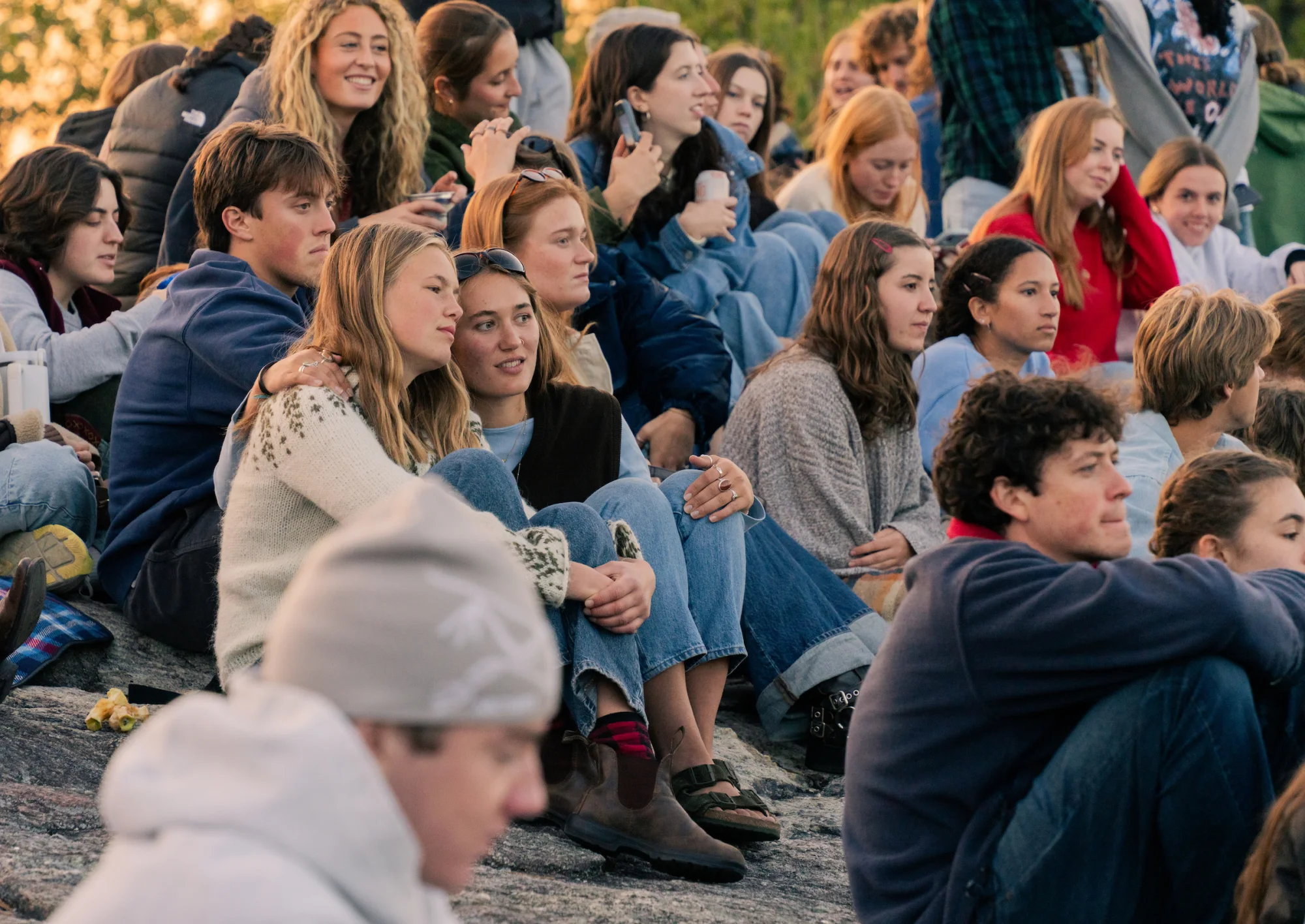 People sit huddled on a large rock