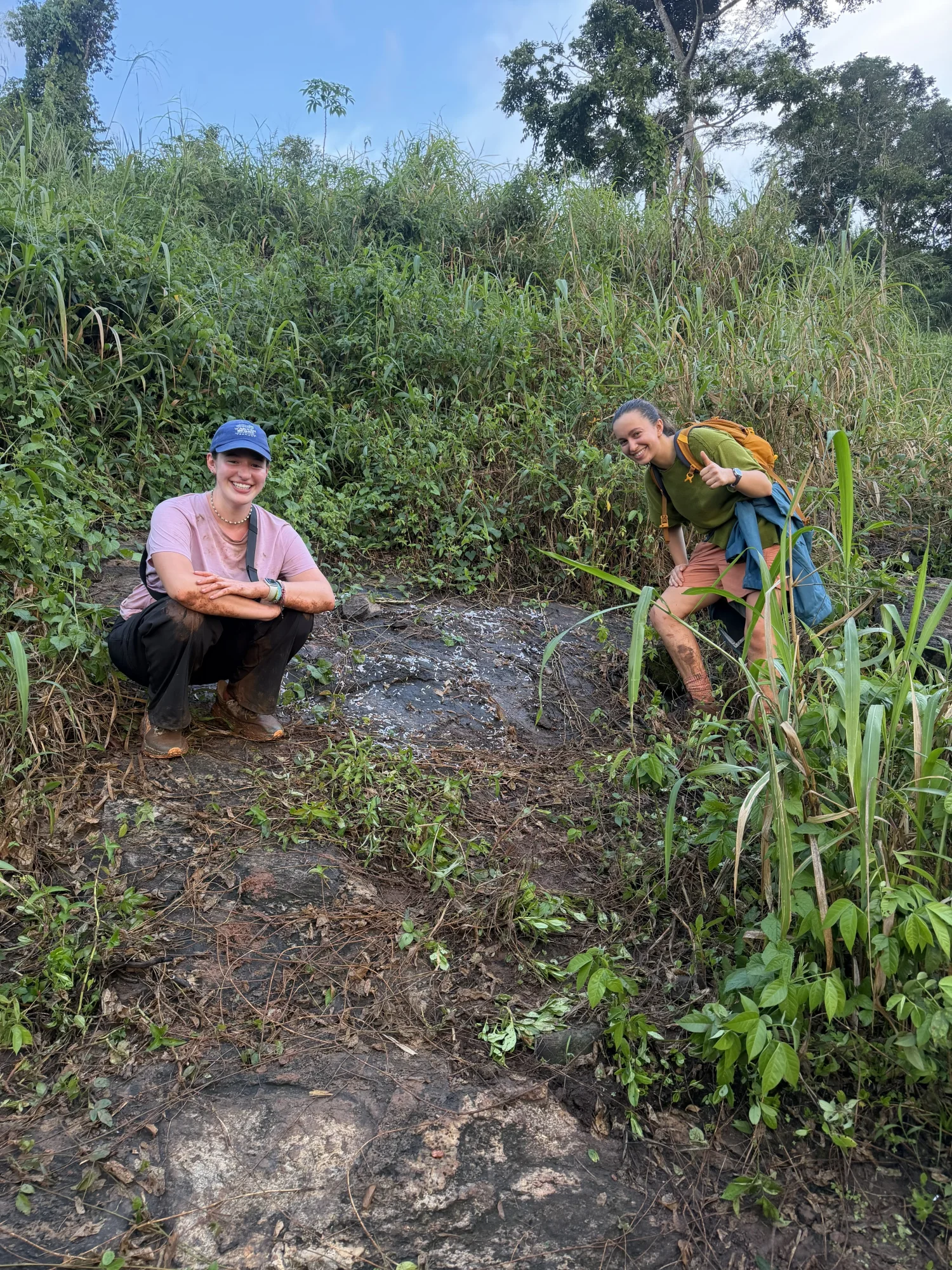 Two women stand in mud during a hike