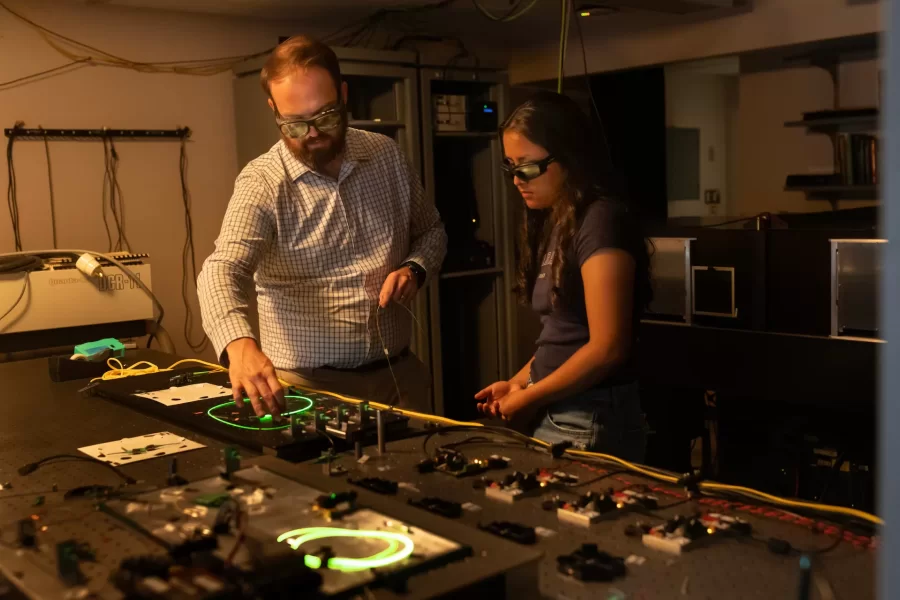 Assistant Professor of Physics Ryan Cole works with students in his Carnegie Science 156 lab on June 20, 2025. There is a secondary lab pictured in some of the photos that he and Paloma visited wearing goggles, where they used a laser to measure light frequencies.
“Every once in a while, science makes sense,” he said at one point to the students.
“Paloma is building an instrument to study very precisely sunlight and specifically the spectrum of sunlight for applications ultimately in exoplanets (planets orbiting other stars) detection and characterization.
And then this table, which is Carson, Quinn, and Audrey (and Andrew Liu who is not here today) They are measuring how atmospheric gases like methane — specifically green house gases — interact with light to ultimately help us measure those things better in the atmosphere.
Students photographed:
Audrey Schane ’25, physics major, who is working as a research assistant with Cole this summer,
Shown at the computer (striped t-shirt), where she is looking at a gas sample where she’s building something to control gas temperatures, with a vaccuum on the bottom.
Paloma Rodriguez ’26, a physics major (black t-shirt)
Carson Moellering ’26, physics major, looking at how methane absorbs light in different conditions (light reflecting back and forth in mirrors (white t-shirt)
Qwynn Kobertz ’26, double major in physics and studio art, using a DSR laser exploring how to use this laser in a methane detecting app. (sunglasses on head) Here are two quick links that may help with some context for what we're doing in the lab.
My research website: https://sites.google.com/bates.edu/colelab/research-areas?authuser=0
NIST Article on optical frequency combs: https://www.nist.gov/topics/physics/optical-frequency-combs