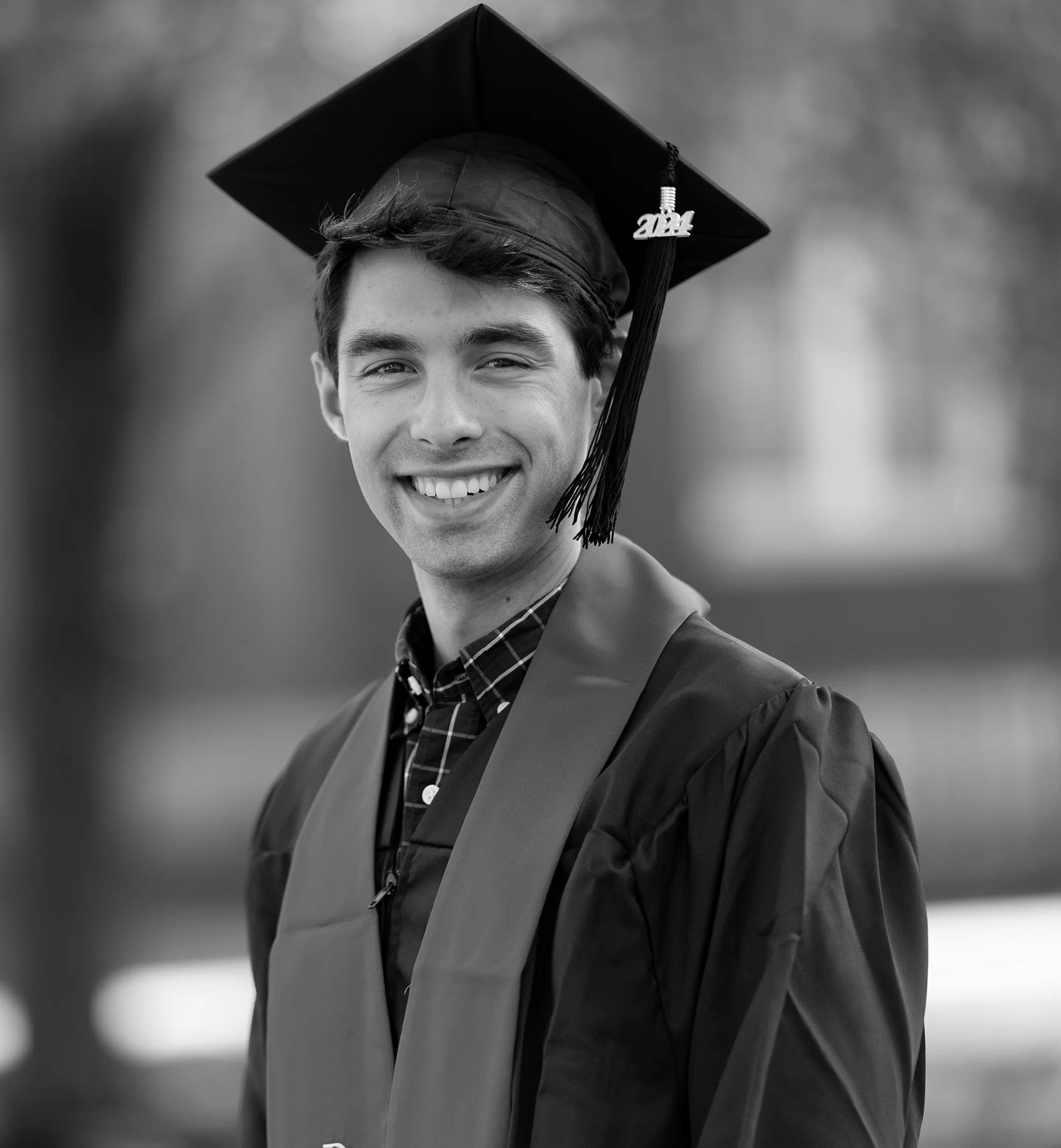 Black and white photo of Jaden standing outdoors wearing a cap and gown