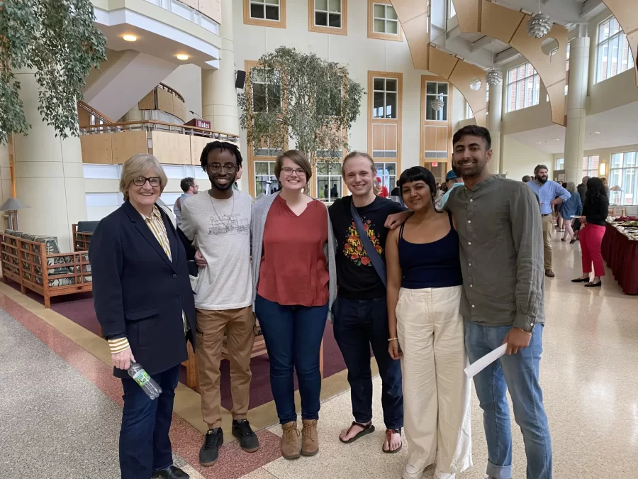 Student members of a Religious Studies Short Term course-design team pose with outgoing Bates President Clayton Spencer at an event in Perry Atrium showcasing innovative Short Term courses. From left: President Spencer, Rashad King ’25, Martha Coleman ’23, Jack Cantor ’23, Khushi Choudhary ’23, Rishi Madnani ’23.